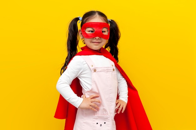 Klein Aziatisch meisje in rood supermankostuum en masker Koreaans kind in superheldenkaap glimlachend