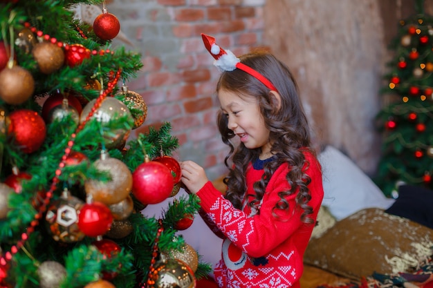 Klein Aziatisch meisje versiert kerstboom glimlachend Kerstmis, nieuwjaar