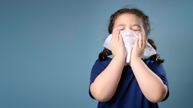 Klein aziatisch meisje ziek en verdrietig met niezen op neus en koude hoest op papieren zakdoekje omdat zwak of virus en bacteriën van stofweer en kleuterschool en kleuterschool voor medisch.