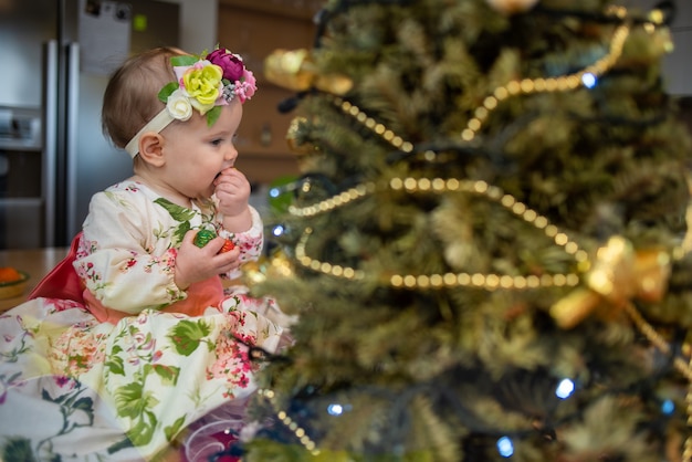 Klein babymeisje bij de kerstboom