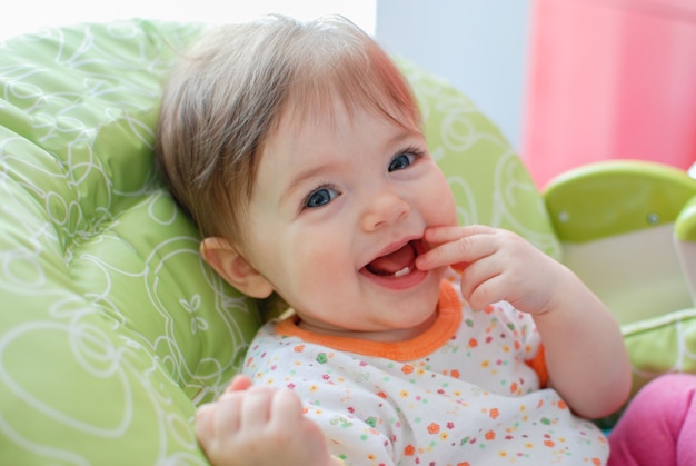 Klein babymeisje in een hoge stoel