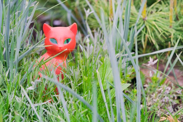 Klein beeldje van een rode kat met groene ogen in het gras