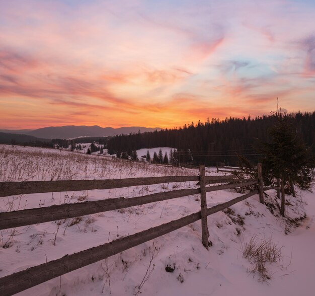 Klein bergdorp en besneeuwde winterbergen in het eerste zonsopgangzonlicht rond Voronenko Karpaten, Oekraïne