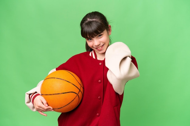 Klein blank meisje dat basketbal speelt over een geïsoleerde achtergrond die lacht