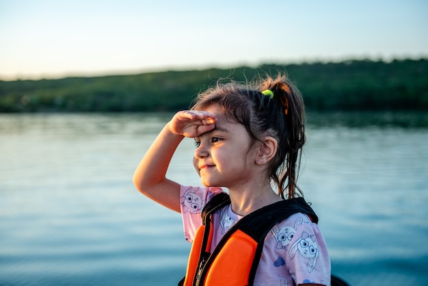 Klein blij meisje in een reddingsvest tijdens het wandelen op een boot