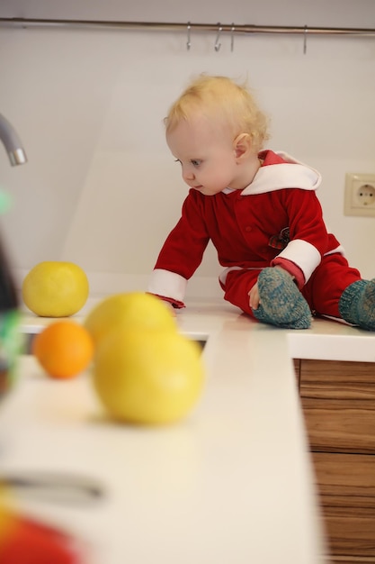 Klein blond kind in de keuken zit op een tafel