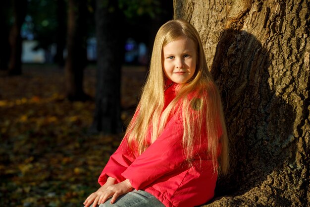 Klein blond meisje in een roze jasje in het park in de herfst