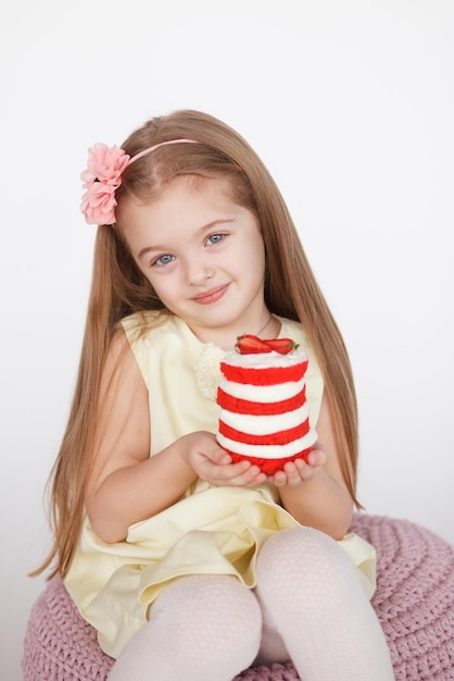 Klein blond meisje met een roodfluwelen cake