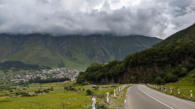Klein dorp in de buurt van de grote groene bergen onder de dikke wolken in de zomer