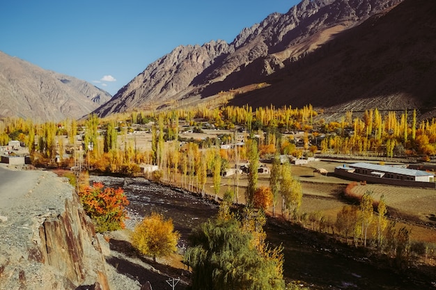 Klein dorp in Gupis-vallei tegen Hindu Kush-bergketen in de herfst