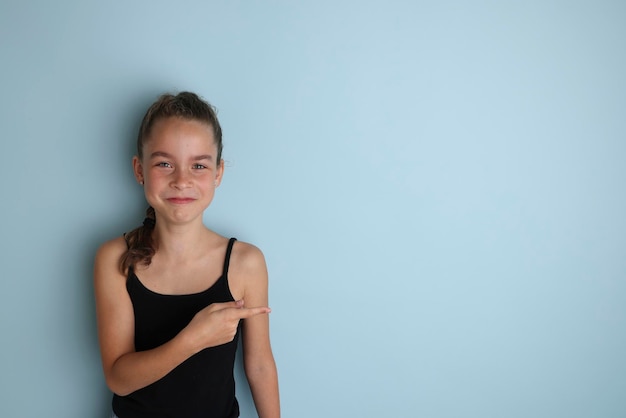 Klein emotioneel tienermeisje in een zwart t-shirt 11 12 jaar oud op een geïsoleerde blauwe achtergrond Children39s studioportret Plaats de tekst om de plaats voor de inscriptie te kopiëren