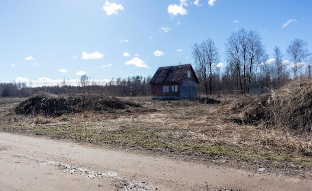 Klein en oud landhuis in het veld met kleine bomen in het voorjaar