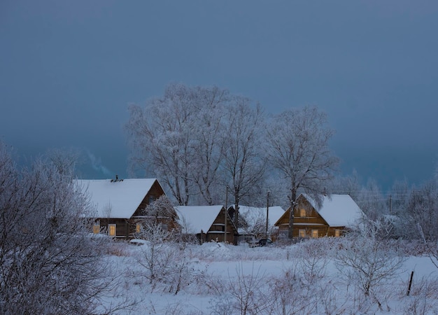 Klein gezellig dorpje met houten huizen in sneeuw mooie winteravond