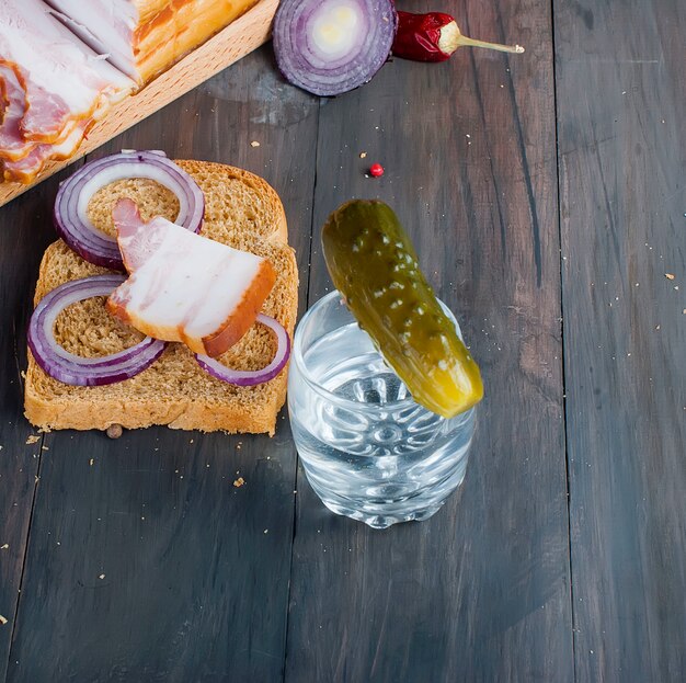 Klein glas met Russische wodka, sandwich met gerookt spek en zoute komkommer