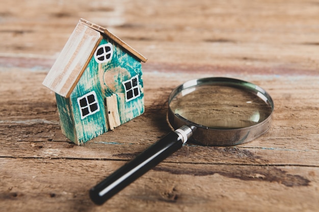 Klein huis en een vergrootglas op een houten tafel