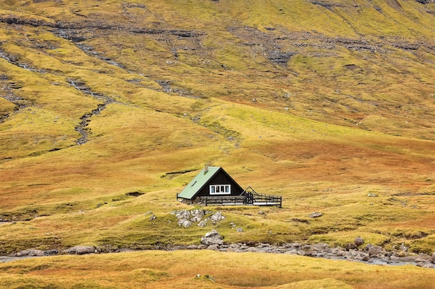 klein huis staat in een geweldige herfstvallei Faeröer