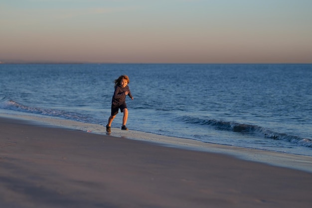 Klein jongenskind dat langs de oceaan rent Kid rent op zandstrand Zomervakantie met kind