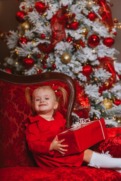 klein kind in rode jurk met kerstboom