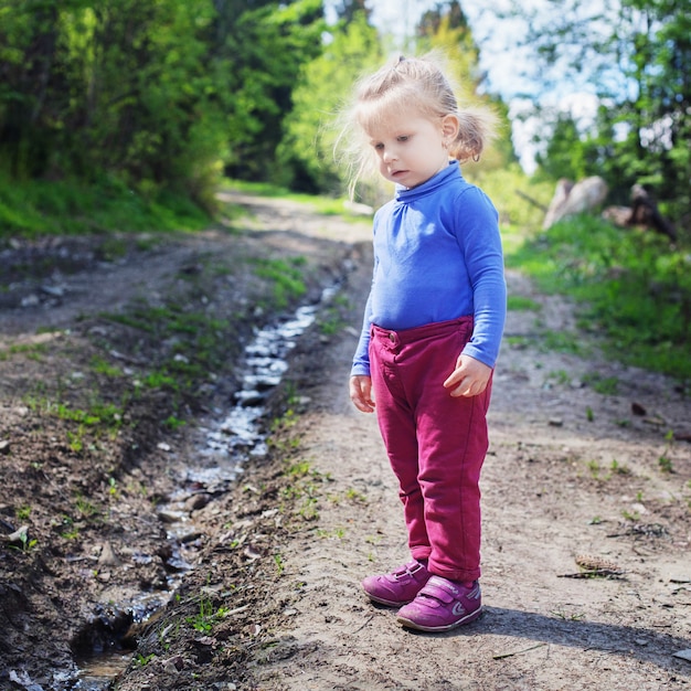 Klein kind kijkt naar de kreek in het bos.