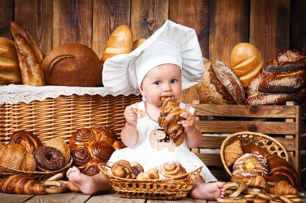 Klein kind kookt een croissant in manden met broodjes en brood.