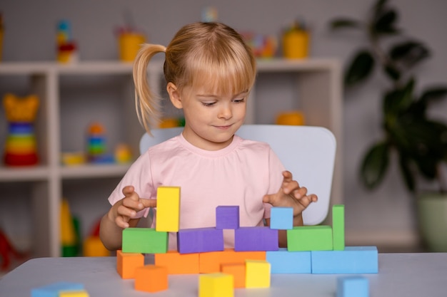 Klein kind meisje houten speelgoed thuis of kleuterschool spelen