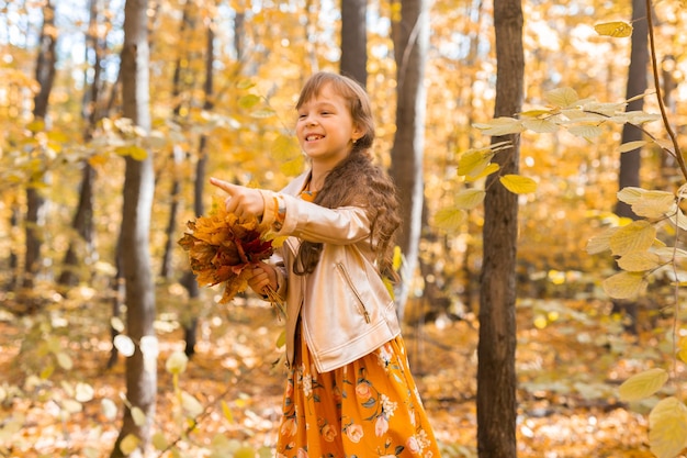 Klein kind meisje met herfst oranje bladeren in een park levensstijl herfst seizoen en kinderen concept