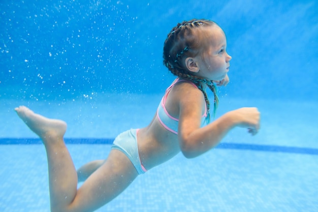 Klein kind meisje onderwater zwemmen in het peuterbad Duiken Baby kind leren zwemmen Geniet van zwemmen en bubbels