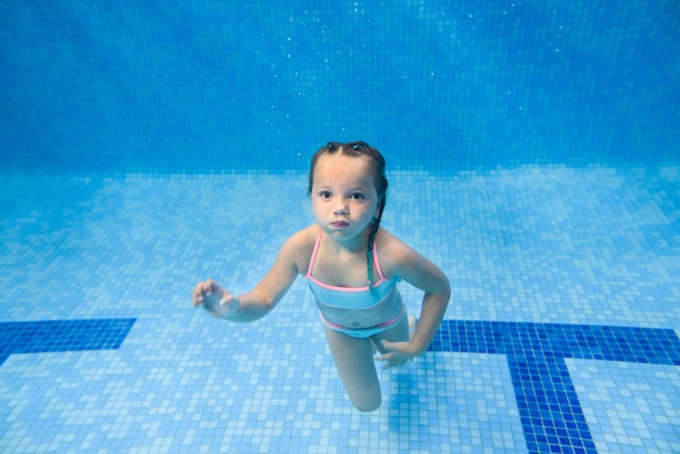 Klein kind meisje onderwater zwemmen in het peuterbad Duiken Baby kind leren zwemmen Geniet van zwemmen en bubbels