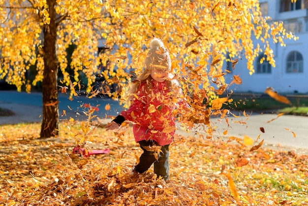 klein kind meisje spelen met bladeren in herfst park