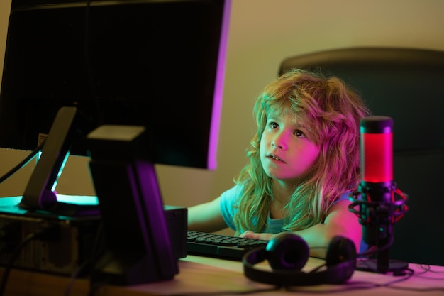 Klein kind met behulp van desktop-pc 's nachts kind jongen verlicht door het blauwe licht van een computerscherm Gamer spelen desktopcomputerspel Kind met behulp van computertechnologie in huis