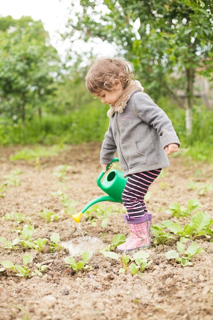 Klein kind met gieter in de tuin