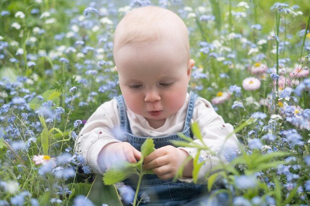 Klein kind met plezier en het verkennen van de natuur vrolijk babymeisje in bloemenweide