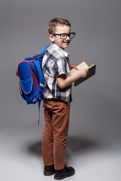 Klein kind met schooltas en boek. Jonge leerling met rugzak en leerboek