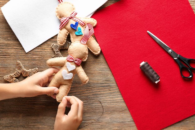 Klein kind naait kerstspeelgoed van vilt aan tafel