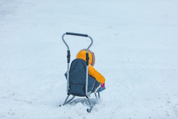 Klein kind op slee die langs de winterheuvel naar beneden glijdt