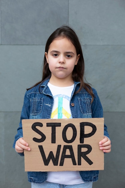 Klein kind op straat met een handgemaakt bord met de slogan Stop War