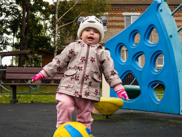 Klein kind spelen met een bal op de speelplaats op een herfstdag