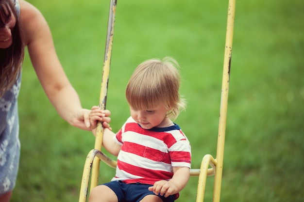 Klein kind swingend op speelplaats in de tuin