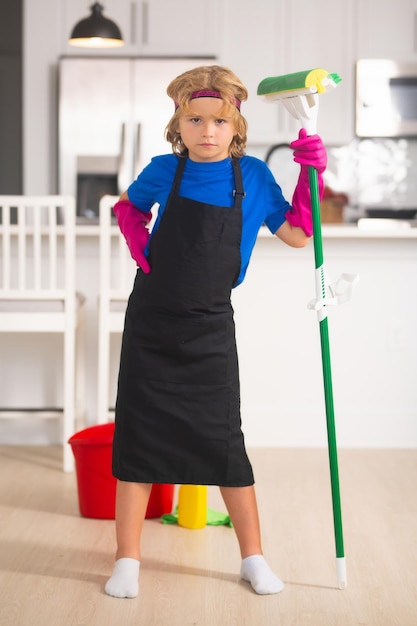 Klein kind thuis schoonmaken Kind doet huishoudelijk werk met plezier Portret van kind huishoudster met natte platte dweil op keuken interieur achtergrond