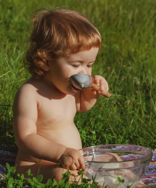 Klein kind voeden met een lepel Leuke grappige baby met lepel in mond Lente voor kinderen op het platteland Eco leven