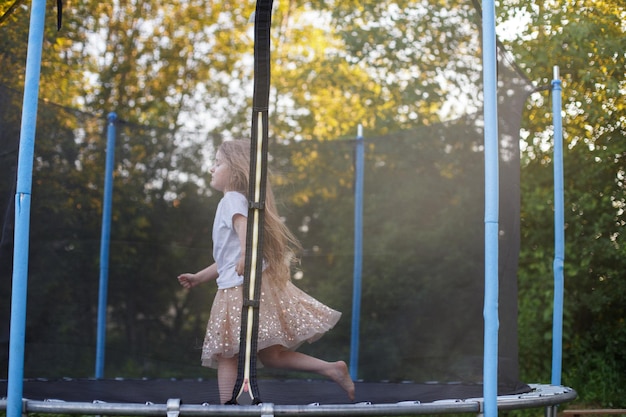 Klein kindmeisje dat op de trampoline in de achtertuin springt