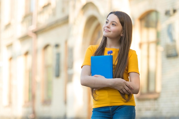 Klein kindmeisje terug naar school houdt leerboek academisch jaarconcept vast