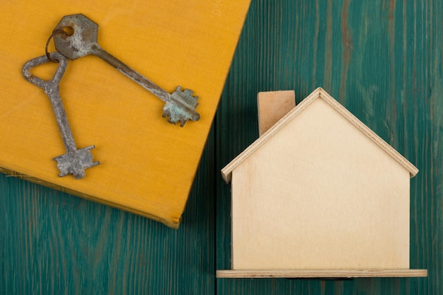 Klein leeg huis en sleutel op blauw houten bureau