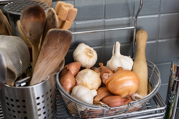 Klein mandje in de keuken naast het keukengerei met knoflook, uien en sjalotten.