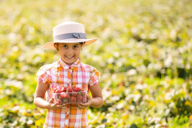 klein meisje aardbeien plukken in het veld