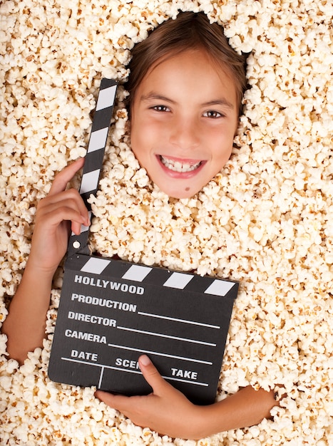 klein meisje begraven in popcorn met film klepel bord