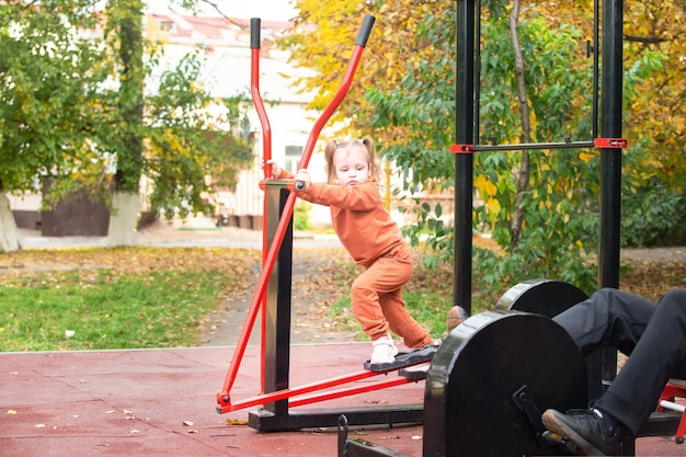 klein meisje besteedt tijd aan fitnessapparatuur voor buiten