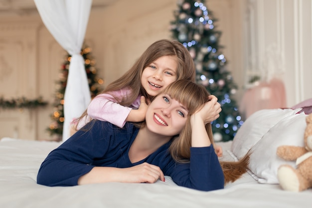 Klein meisje brengt tijd door met spelen met moeder terwijl ze in bed ligt. Kerst verhaal. Gelukkige jeugd.