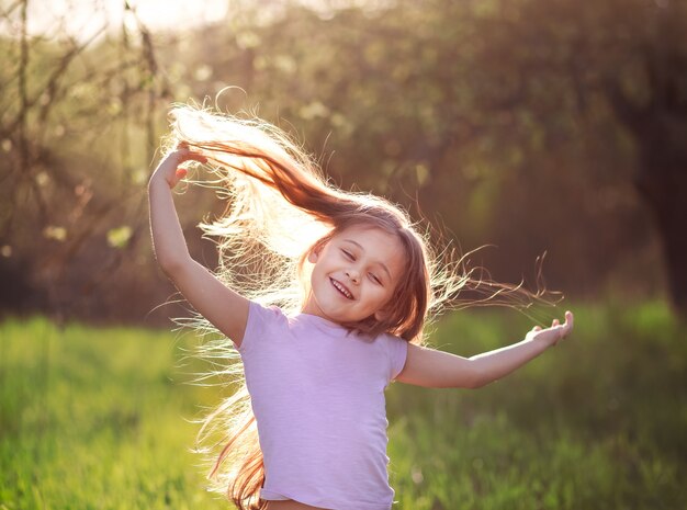 Klein meisje dansen in de natuur in de zomer met lang haar