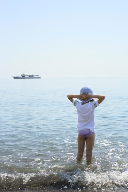 Klein meisje dat aan het water staat en naar het schip kijkt